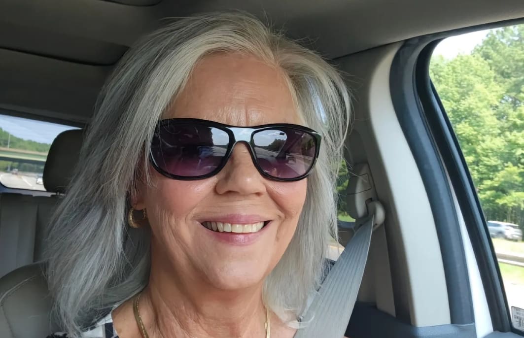 A woman with sunglasses in the back of a car.