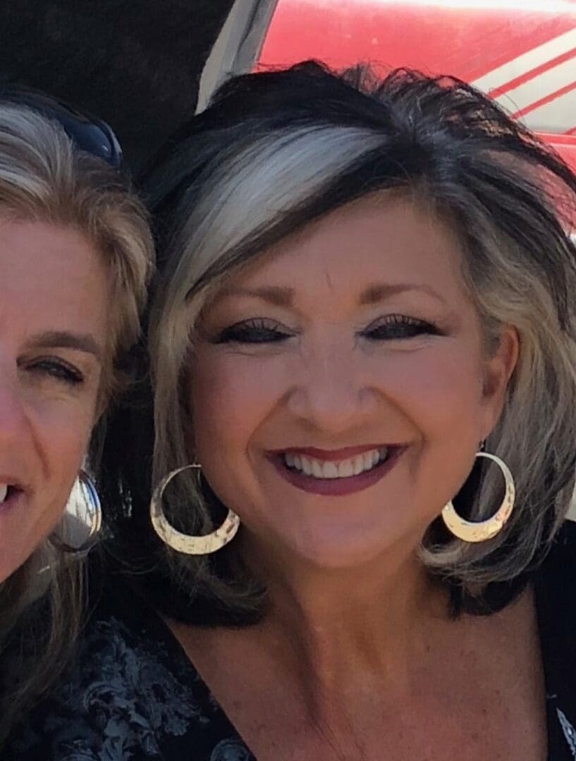 Two women with big earrings smiling for the camera.