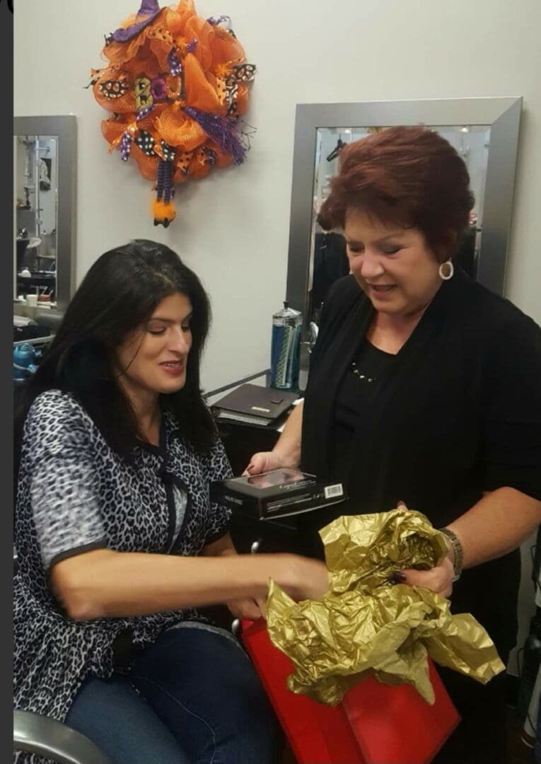 Two women are looking at a gold gift bag.