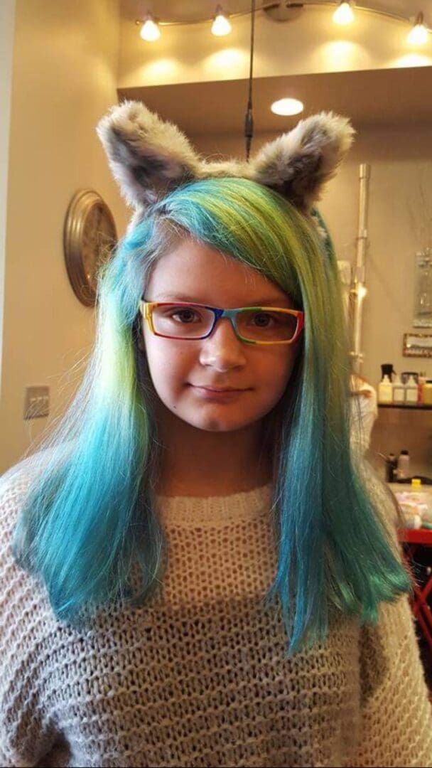 A girl with blue hair and glasses wearing cat ears.